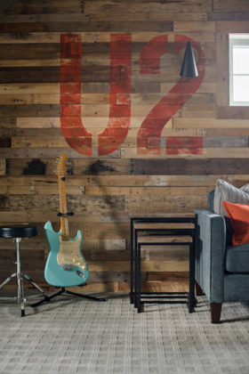 Closeup view of reclaimed wood wall, an upholstered chair, end table, and an electric guitar