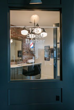 View through a glass window to a room with an office chair and a brick wall