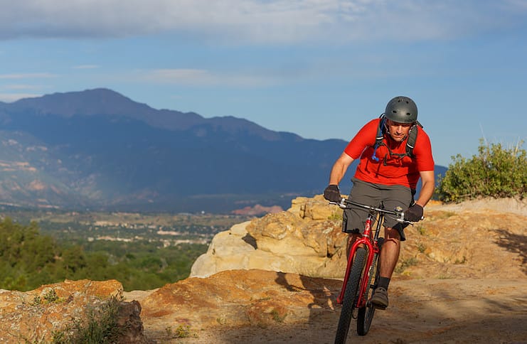 A mountain bikers rides the trails in Palmer Park with Pikes Peak on the horizon.