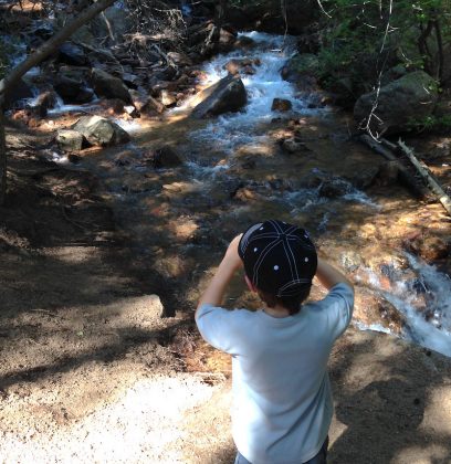 A child hiker views the creek along the Seven Bridges Trail, a great family hike in Colorado Springs.