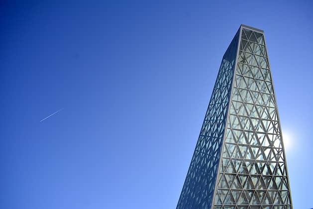 Obelisk-like building with geometric facets against a clear blue sky