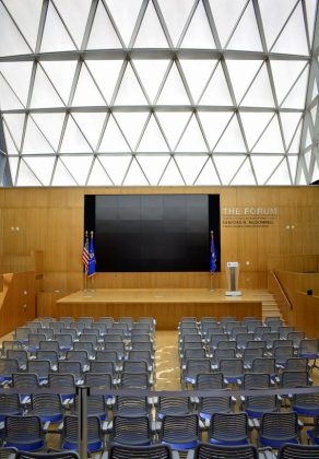 Room with rows of chairs in front of a large screen and a stage