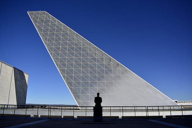 A silver geometric building with a silhouetted figure in front
