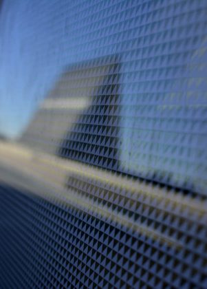 Out-of-focus reflection of a triangular building on a faceted mirror-like surface
