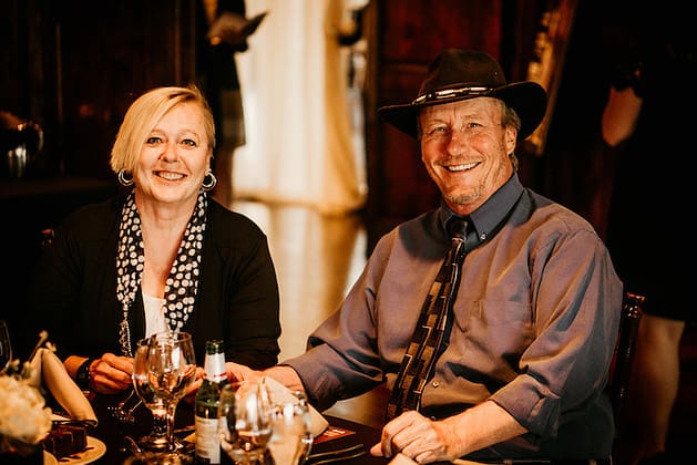 A man and a woman seated at a dining table, smiling at the camera