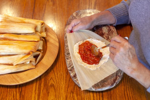 spreading red chile on masa for the tamales.