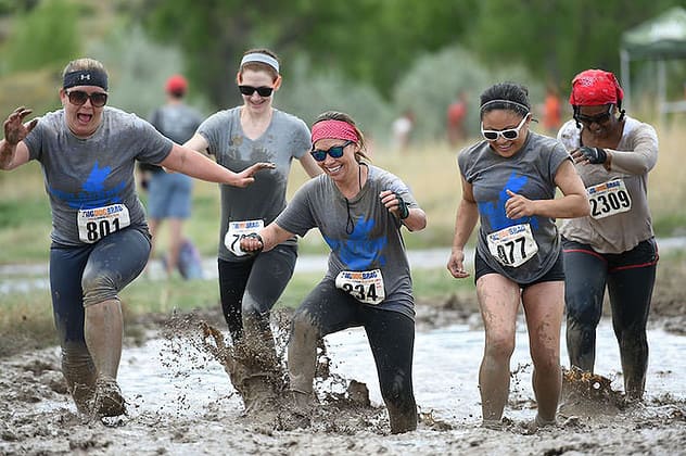 women run through mud at obstacle course races