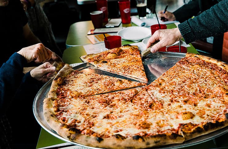 Serving a slice from a huge Fat Sully's New York Pizza