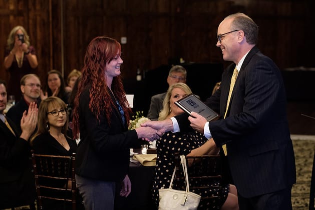 Photo of a man handing a framed award to a woman