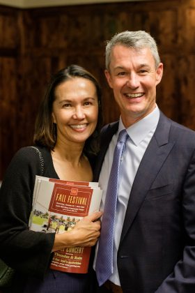 A woman holding brochures next to a man, both smiling at the camera