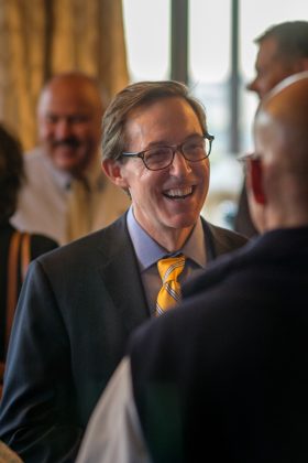 Photo of a man smiling while talking to another man in the foreground