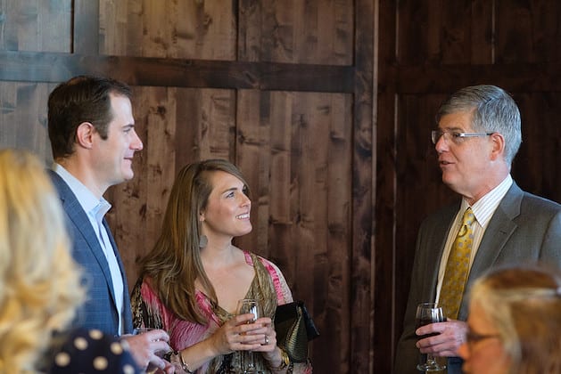 A group holding drinks and talking in a gathering
