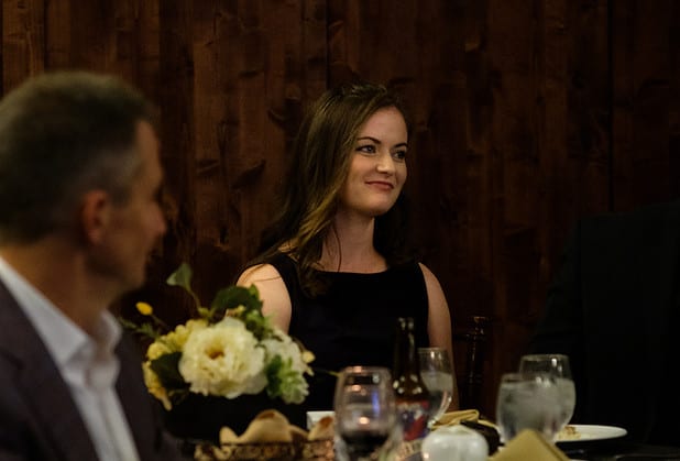 Smiling woman at a dining table with flowers in the foreground
