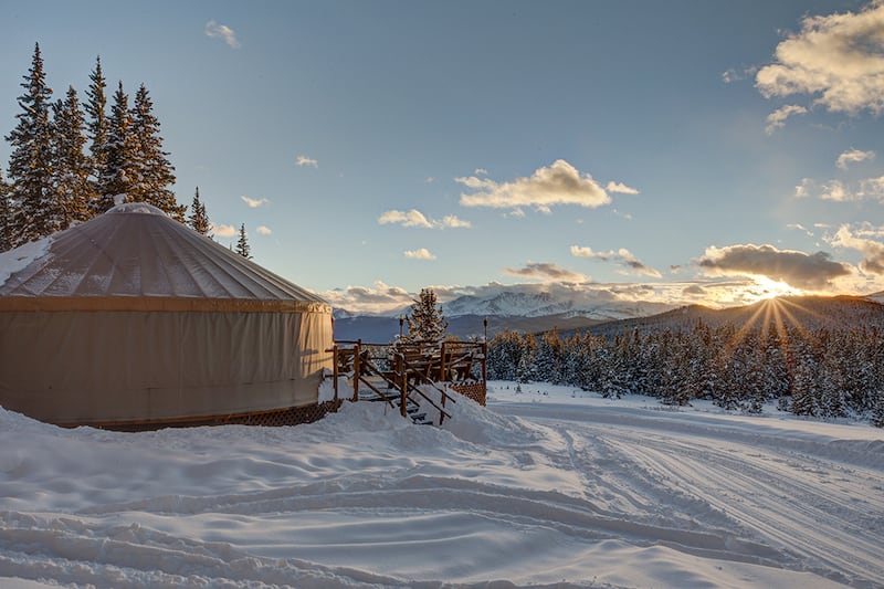 A snowy sunset scene at the Tennessee Pass Cookhouse Yurt, where you can snowshoe or ski to dinner - an excellent Colorado gift experience