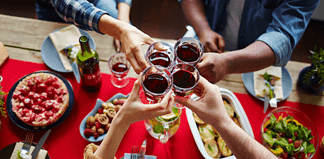 Arms stretched to cheers Thanksgiving wine over dinner