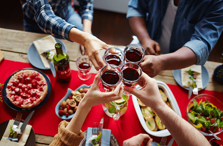 Arms stretched to cheers Thanksgiving wine over dinner