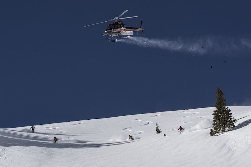 Group of skiers makes first tracks with helicopter overhead during a Telluride Helitrax ski trip, a great Colorado holiday gift experience.