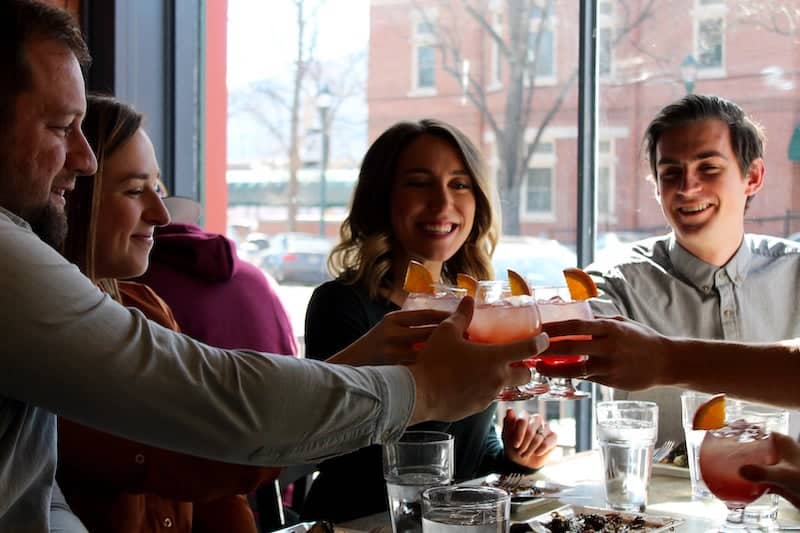 A group of diners raises glasses in cheers on a Rocky Mountain Food Tour of downtown Colorado Springs, a great holiday gift experience for foodies