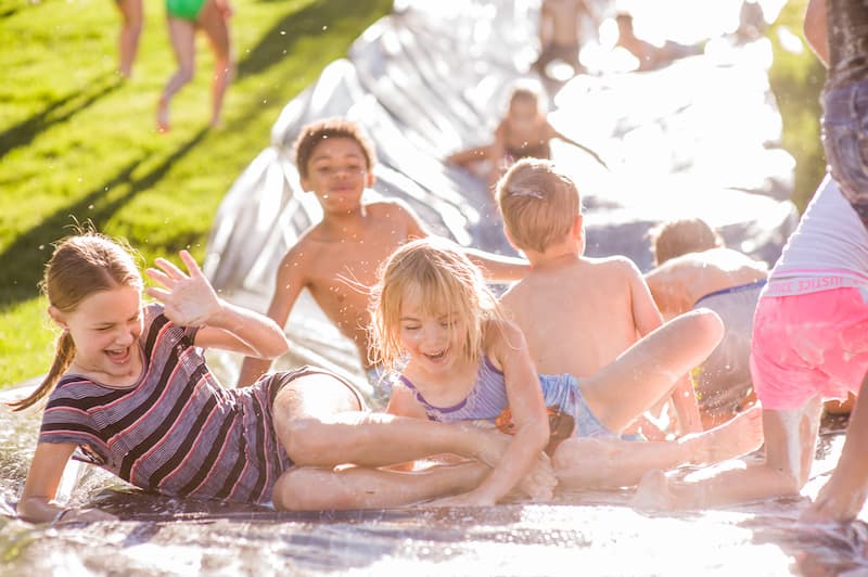 Kids laughing on the slip and slide at a Music on the Mesa concert at Gold Hill Mesa in Colorado Springs