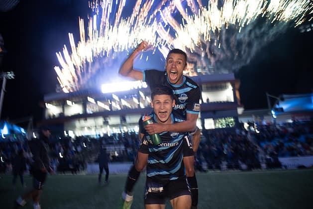 Switchbacks FC soccer players celebrate win with fireworks in the background.