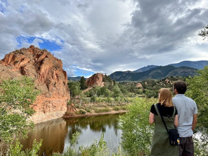Couple standing beside lake and cliffs at Red Rock Open Space near Manitou Springs