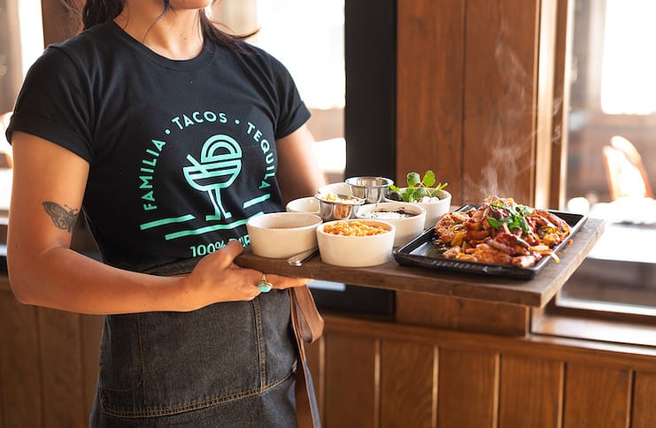 Server with a tray of entrees and sides at My Neighbor Felix, opening its first Colorado Springs location in August 2023.