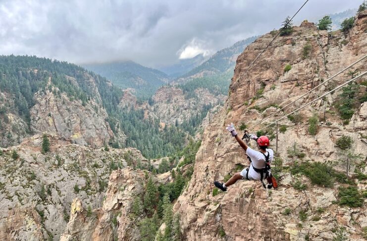 A zip liner whoops across Cheyenne Canon on the Broadmoor Soaring Adventure zip lines in Colorado Springs