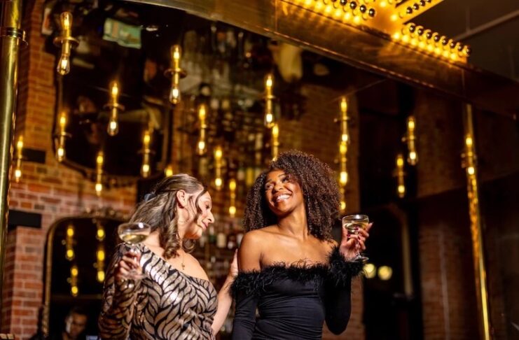 Two women celebrate with champagne in the lobby of the Mining Exchange Hotel for New Year's Eve.