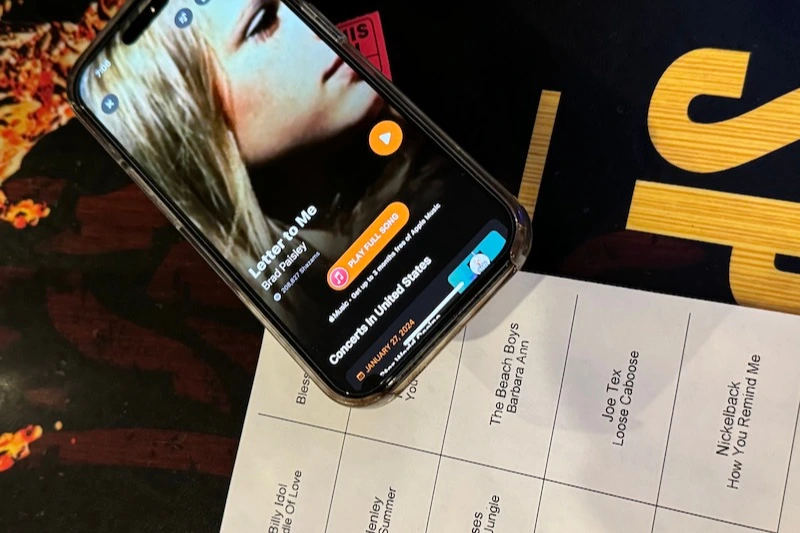Hitmix music video bingo card and phone pulling up the set list.