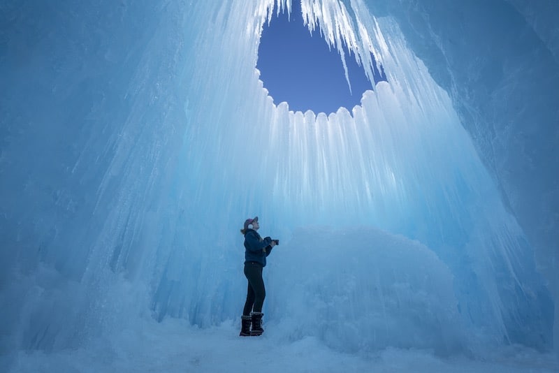 A photographer stands instead a tower of ice at the Colorado Ice Castles