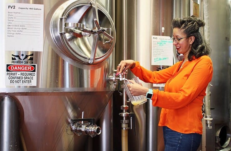Kat Hess, the new female head brewer at Phantom Canyon Brewing samples from the brew tank