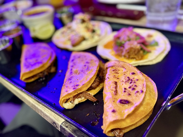 Quesabirria tacos under the neon lights at Por Favor Tacos and Tragos. 