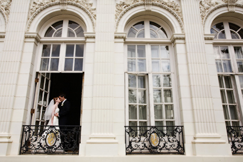 A bride and groom kiss in a window of the Trianon at the Colorado Springs School.