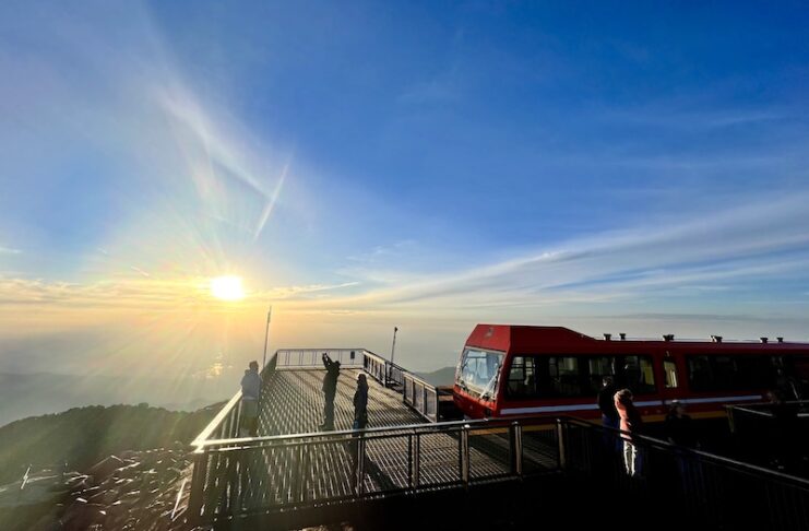 People take photos from the observation deck of sunrise on Pikes Peak at the Pikes Peak Summit Visitor Center.