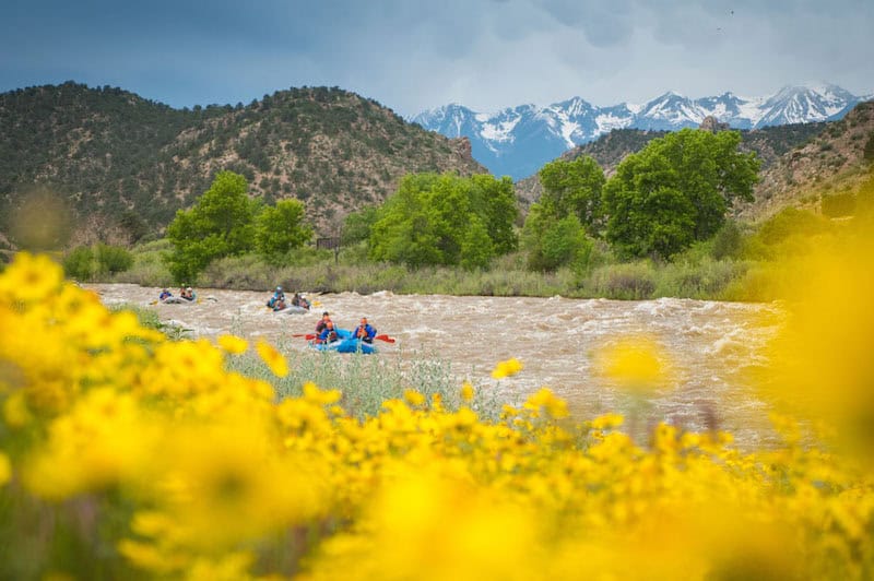 Snow capped Rocky Mountain peaks over white water rafting trip in Colorado on the Arkansas River