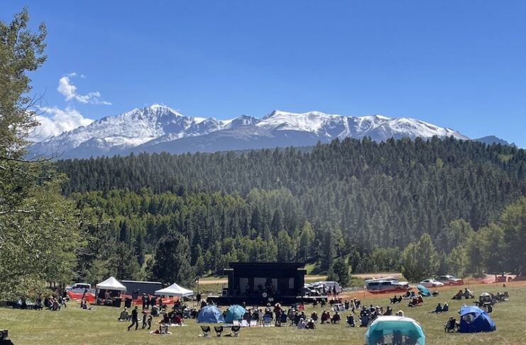Music lovers listening to live music on stage with Pikes Peak in the background of the Mountain of the Sun Music Festival in Woodland Park, Colorado.