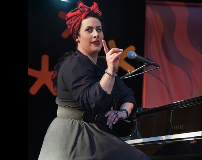 Davina and the Vagabonds front woman plays piano and wags a finger on stage.