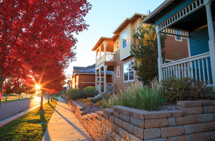 The sun sets through red fall color leaves on the front porch lined sidewalks and streets of Gold Hill Mesa
