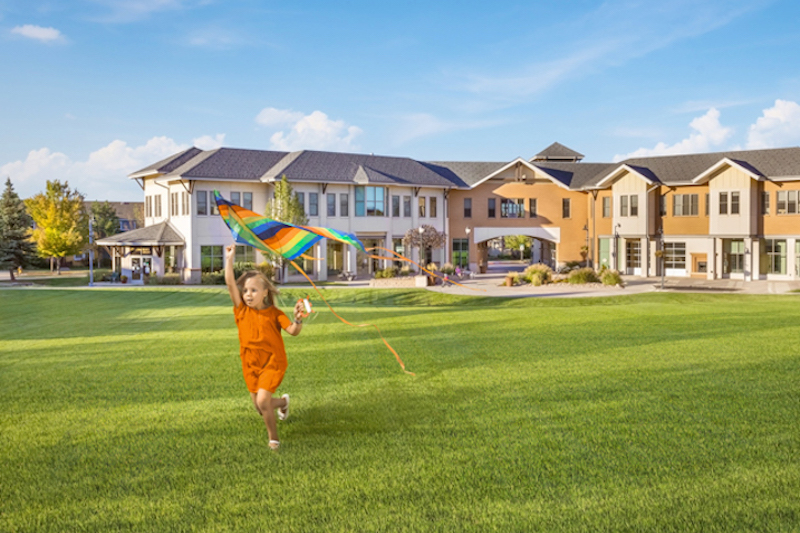 Girl flies a colorful kite one the lawn of the Gold Hill Mesa Community Center