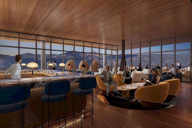 View of the chic interior of Aviators Rooftop Bar at the new Hotel Polaris with mountain views beyond the walls of windows.