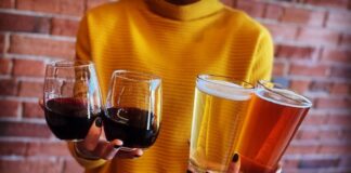 Woman holding two beers and two glasses of wine at Odyssey Gastropub, one of the best spots for happy hour in Colorado Springs