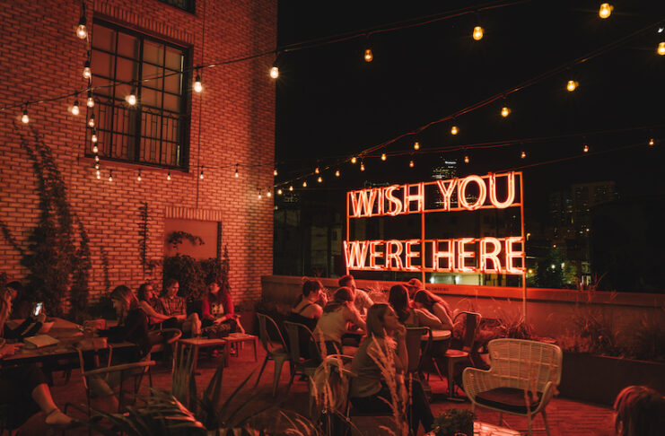 Neon wish you were here sign at night in the Garden at the Ramble Hotel, one of the best Denver hotels