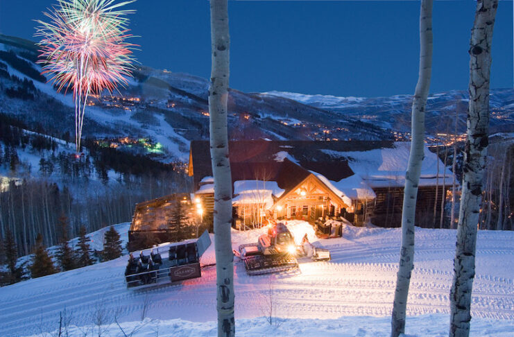 A sleigh is parked in front of Allie's Cabin at Beaver Creek with fireworks colorfully lighting up the sky above Beaver Creek ski resort. The site is part of the Alpine Table events, where Colorado Michelin star restaurants collaborate with Beaver Creek's cabin restaurants.