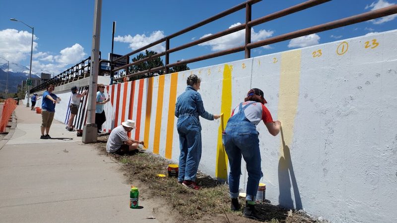 Volunteers paint colors on a wall through the Downtown Creative District.