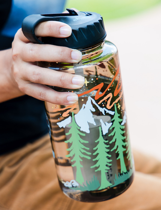Woman holds an artist series Epic Water Nalgene filtered bottle