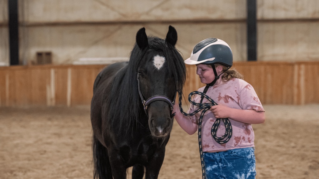 A young girl pets a horse as part of a program through FaithfulHearts Equine Learning Center, a nonprofit participating in the Give Campaign 2025 