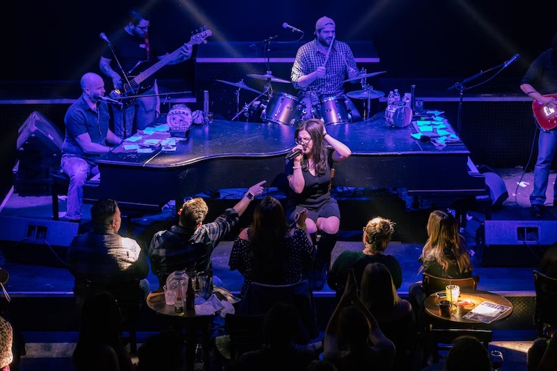 A singer gets down on stage with the band at Louie Louie's dueling piano bar in Colorado Springs.