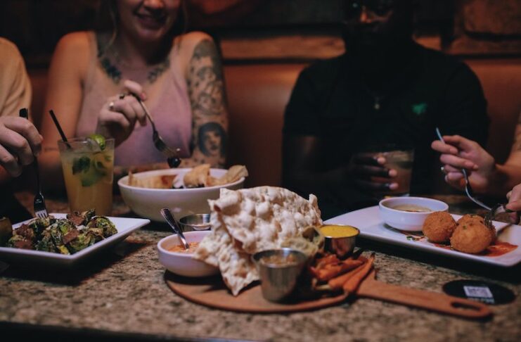 People eating a table full of food at the Rabbit Hole, one of the most popular restaurant reservations in Colorado Springs.