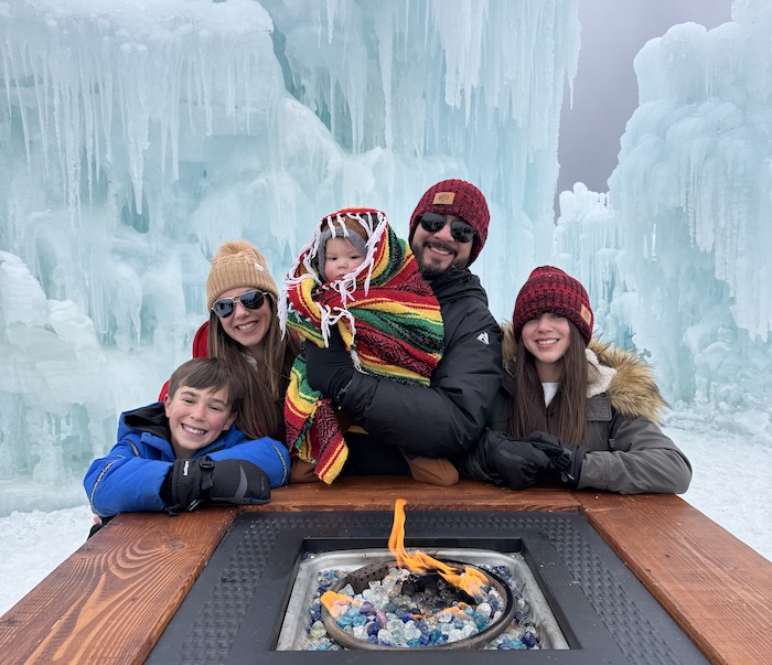 Author Dionne Passacantando and family warm up beside a fire pit at Ice Castles in Cripple Creek, Colorado.