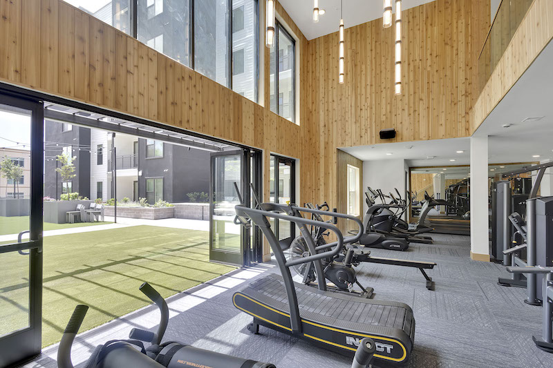 Treadmills and indoor outdoor walls in the two-story fitness center at Fiona, a luxury apartment property in downtown Colorado Springs. 